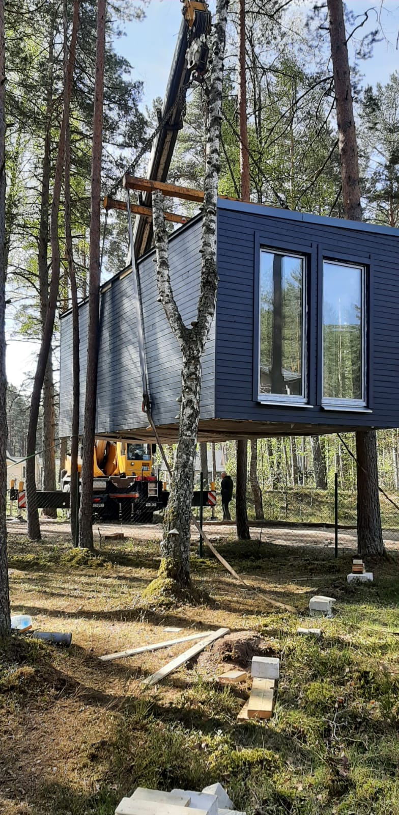 Modern modular home exterior with large windows and wooden deck at sunset